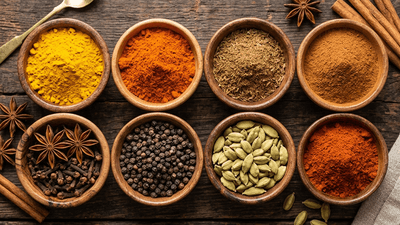 Colorful array of spices in wooden bowls on a dark surface
